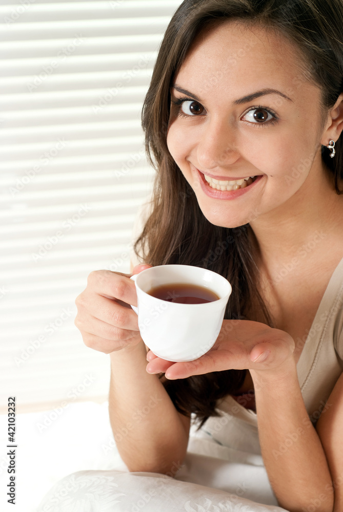 Young Caucasian female sitting with a cup in bed Young Caucasian female sitting with a cup in bed