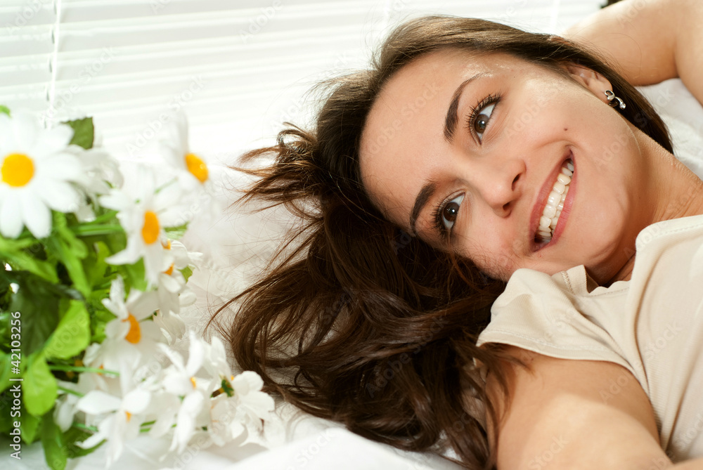 Fototapeta premium Young Caucasian girl lying in bed with flowers