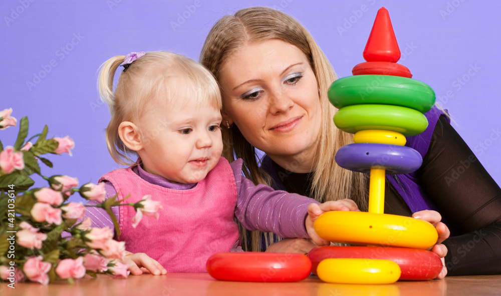 Pretty Caucasian mama with her daughter play with a pyramid Pretty Caucasian mama with her daughter play with a pyramid
