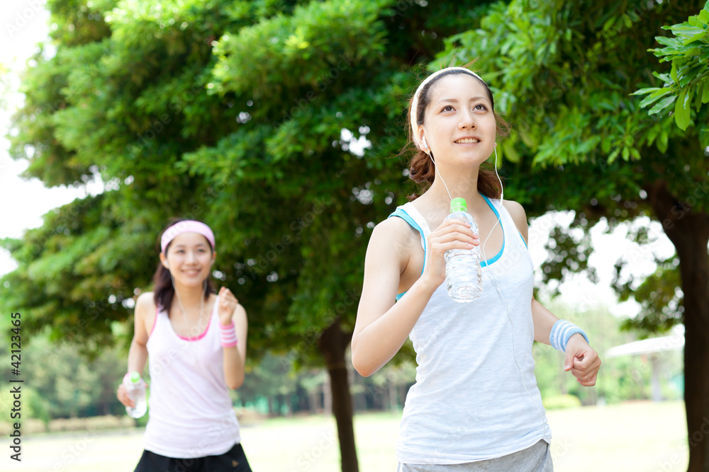 Fototapeta premium Beautiful young women running in park. Portrait of asian.