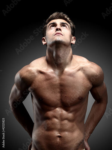 portrait of young strong man against black background