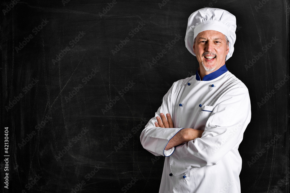 Handsome chef in front of a blackboard