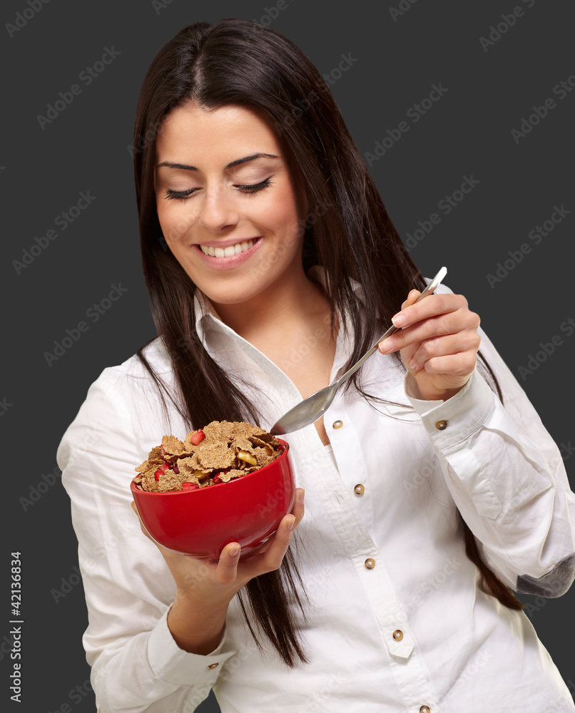 portrait of healthy young woman eating cereals over black portrait of healthy young woman eating cereals over black
