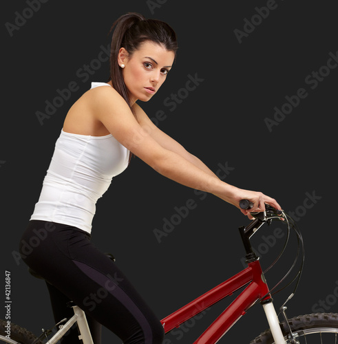 portrait of young woman cycling over black background