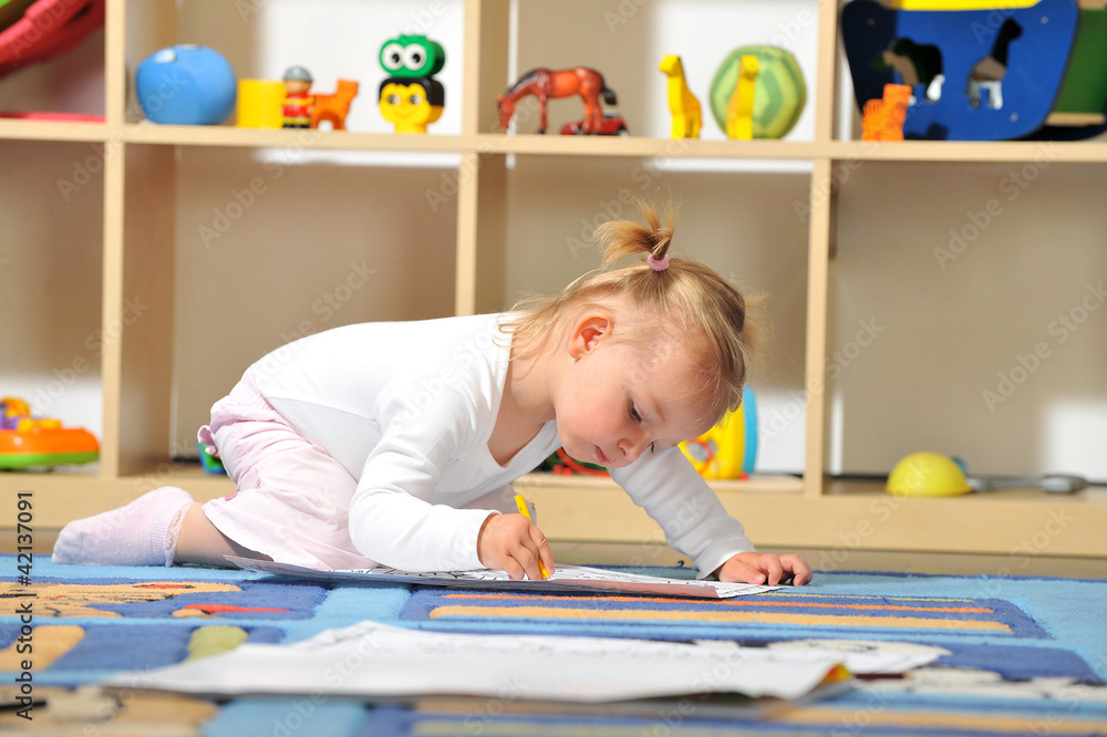 Fototapeta premium Kleines Mädchen malt mit Buntstiften