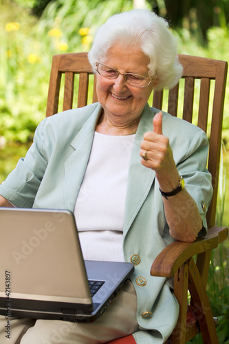 ältere Frau im Garten mit Laptop