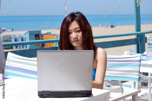 Asian girl on the beach with laptop1 photo