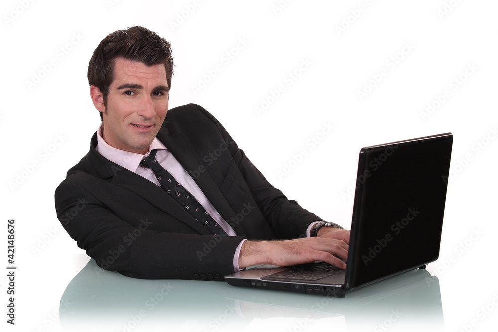Young business mat sat at desk with laptop Young business mat sat at desk with laptop