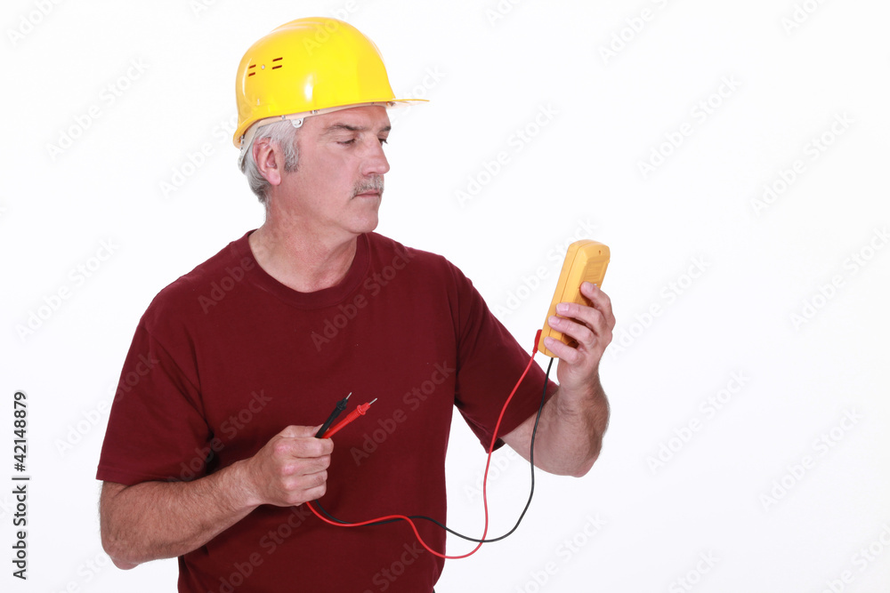 Tradesman looking at his multimeter's display Tradesman looking at his multimeter's display