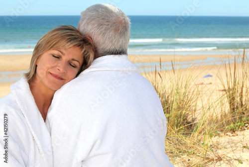 Mature couple in bathrobe on the beach