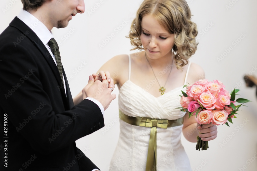 Bride putting a wedding ring on groom's finger, focus on rings Bride putting a wedding ring on groom's finger, focus on rings