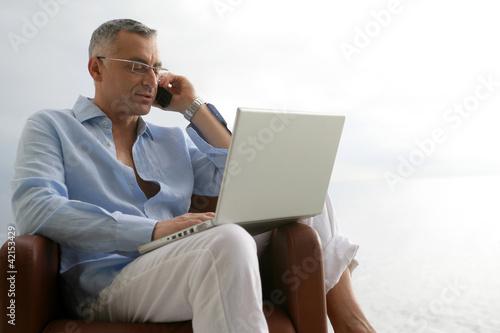 Relaxed man with a laptop and phone