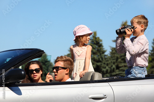 Happy father, mother and two children ride in convertible car © Pavel Losevsky