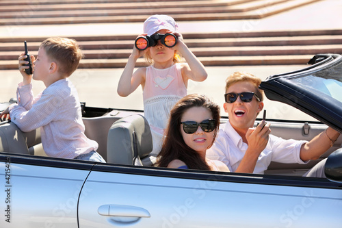 Happy father, mother and two children ride in convertible car