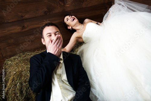 couple in their wedding clothes in barn laughing