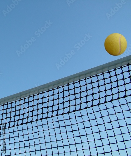 Tennis ball over the net against the blue sky © flik47