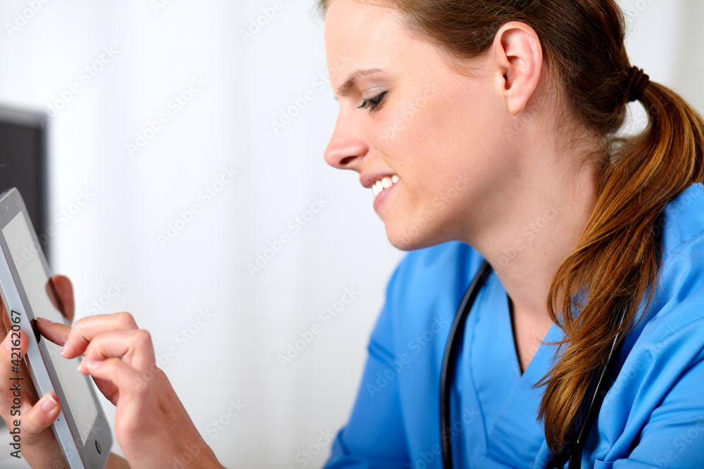 Beautiful friendly nurse smiling with a tablet PC Beautiful friendly nurse smiling with a tablet PC