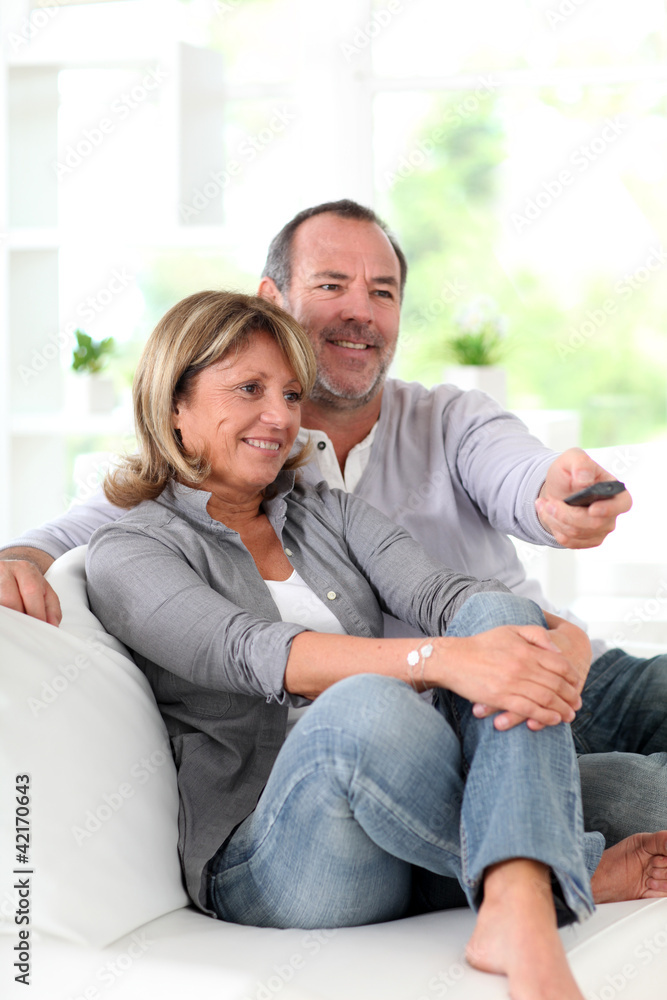 Senior couple watching television at home - obrazy, fototapety, plakaty 