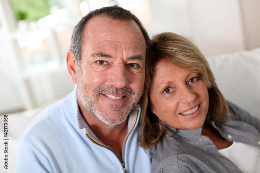 Portrait of happy senior couple sitting in sofa