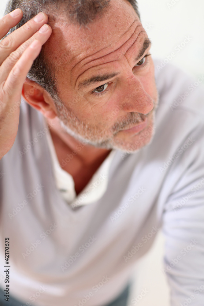 Obraz premium Senior man looking at his hair in mirror