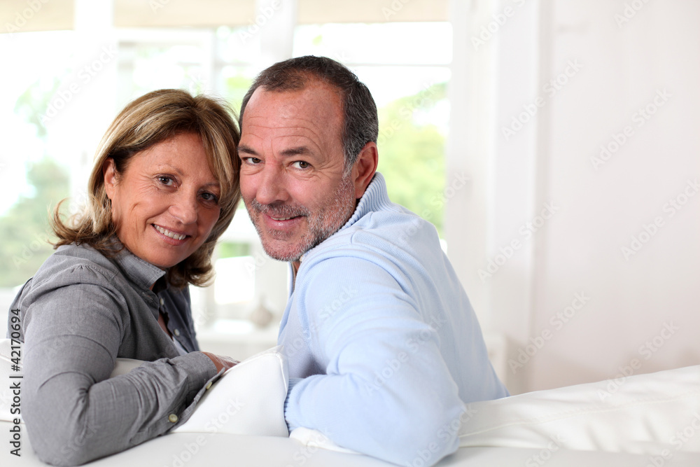 Portrait of happy senior couple sitting in sofa Portrait of happy senior couple sitting in sofa