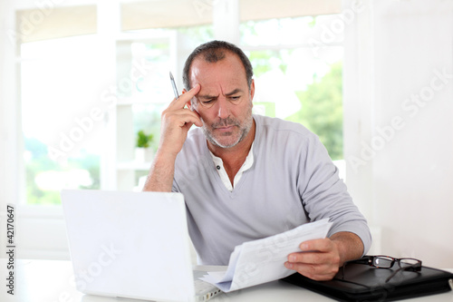 Senior man being puzzled with tax documents photo