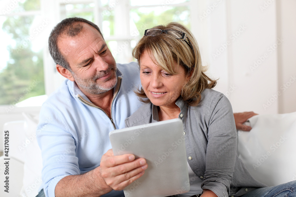 Senior couple looking at web pages on electronic tablet Senior couple looking at web pages on electronic tablet