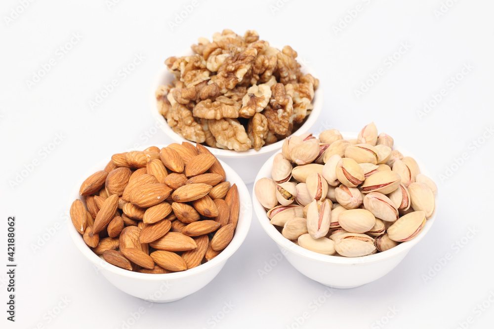 Bowls of almonds,walnuts and pistachios on white background Bowls of almonds,walnuts and pistachios on white background