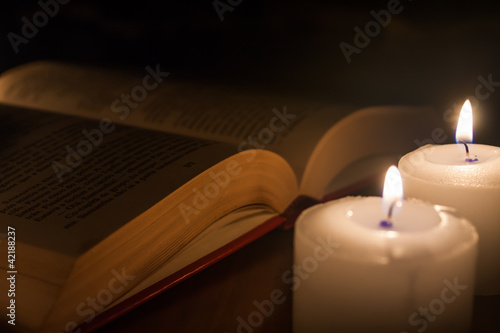 open book and candles on wood table