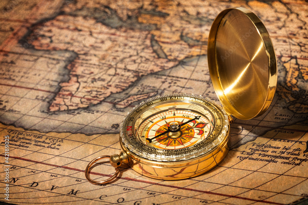 Old vintage golden compass on ancient map