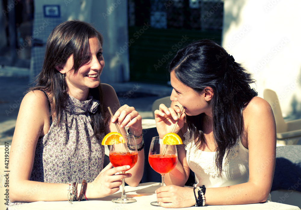 two happy girls while they drink a cocktail two happy girls while they drink a cocktail