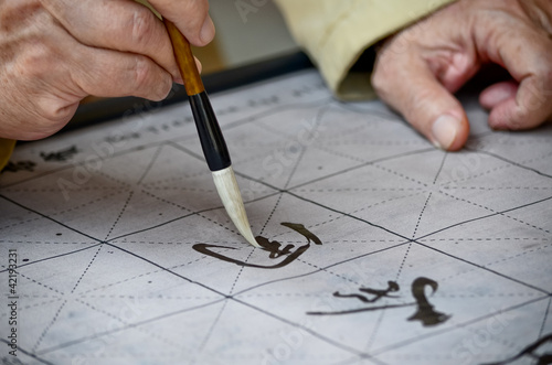 The hands of an elder person writing Chinese calligraphy