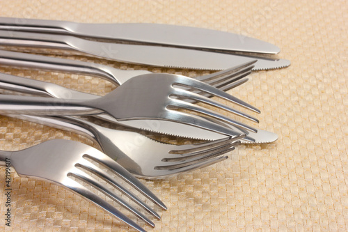 Forks and knives on a beige tablecloth closeup