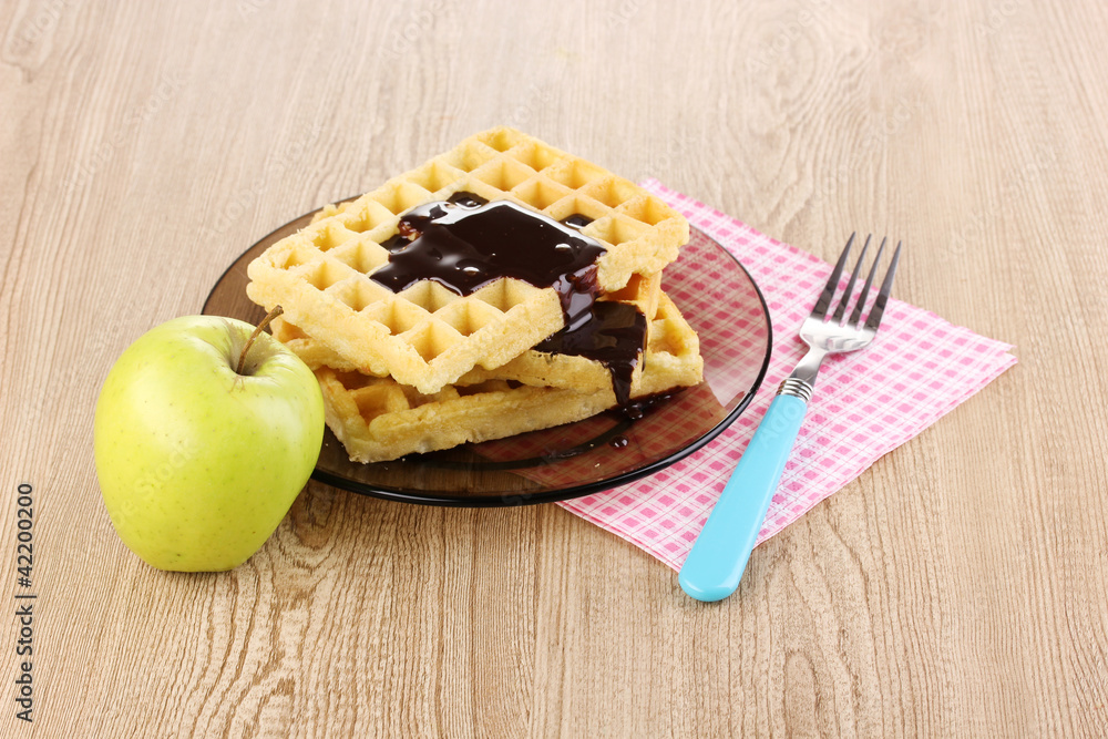 Tasty waffles with chocolate on plate on wooden background Tasty waffles with chocolate on plate on wooden background