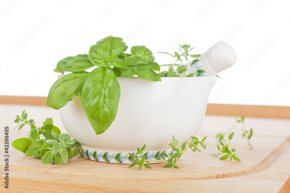 Fresh cooking herbs in mortar on wooden chopping  board.