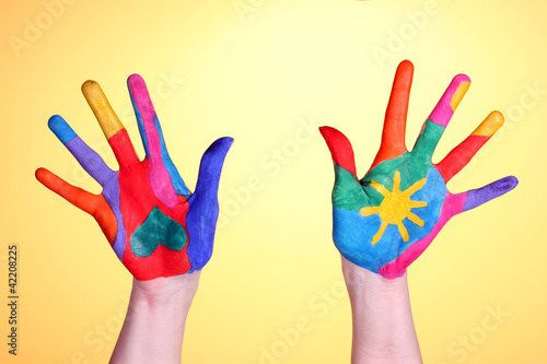 Brightly colored hands on yellow background close-up