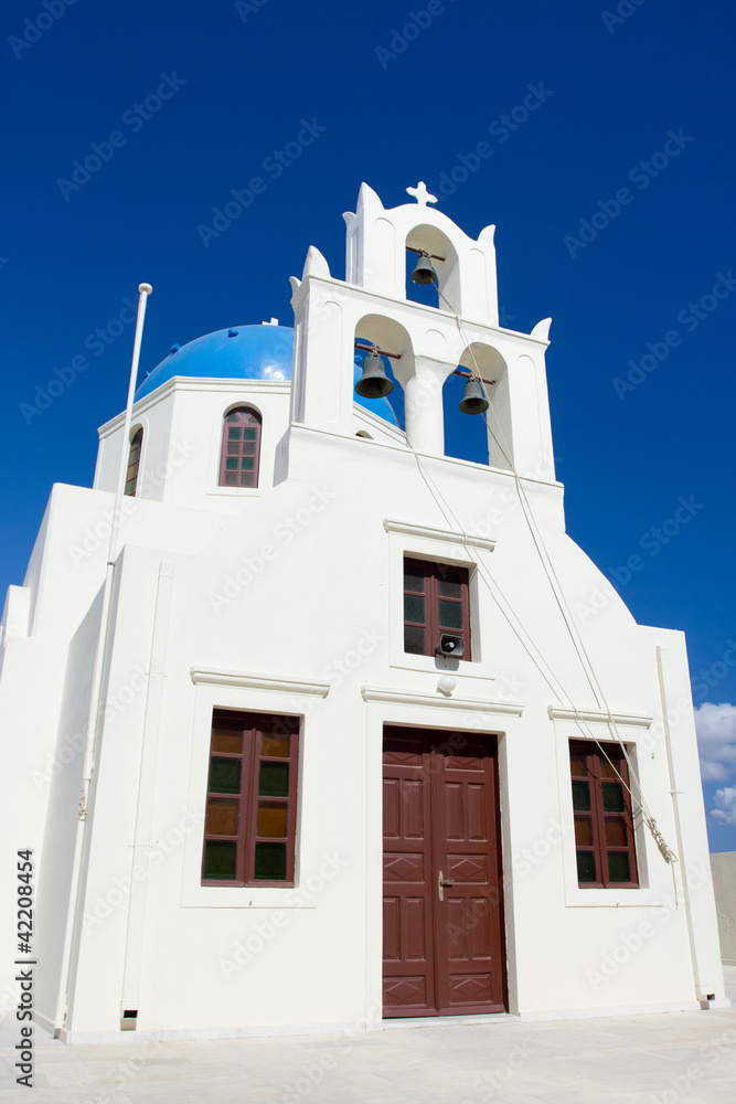 Traditional white church, cross, bells Island Santorini Greece
