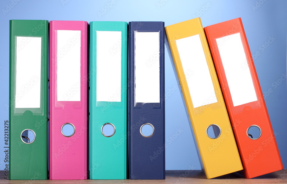 bright office folders on wooden table on blue background bright office folders on wooden table on blue background