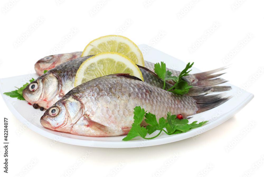 Fresh fishes with lemon and parsley on plate isolated on white Fresh fishes with lemon and parsley on plate isolated on white
