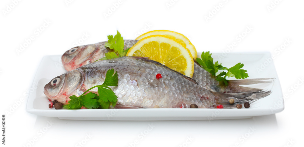 Fresh fishes with lemon and parsley on plate isolated on white Fresh fishes with lemon and parsley on plate isolated on white