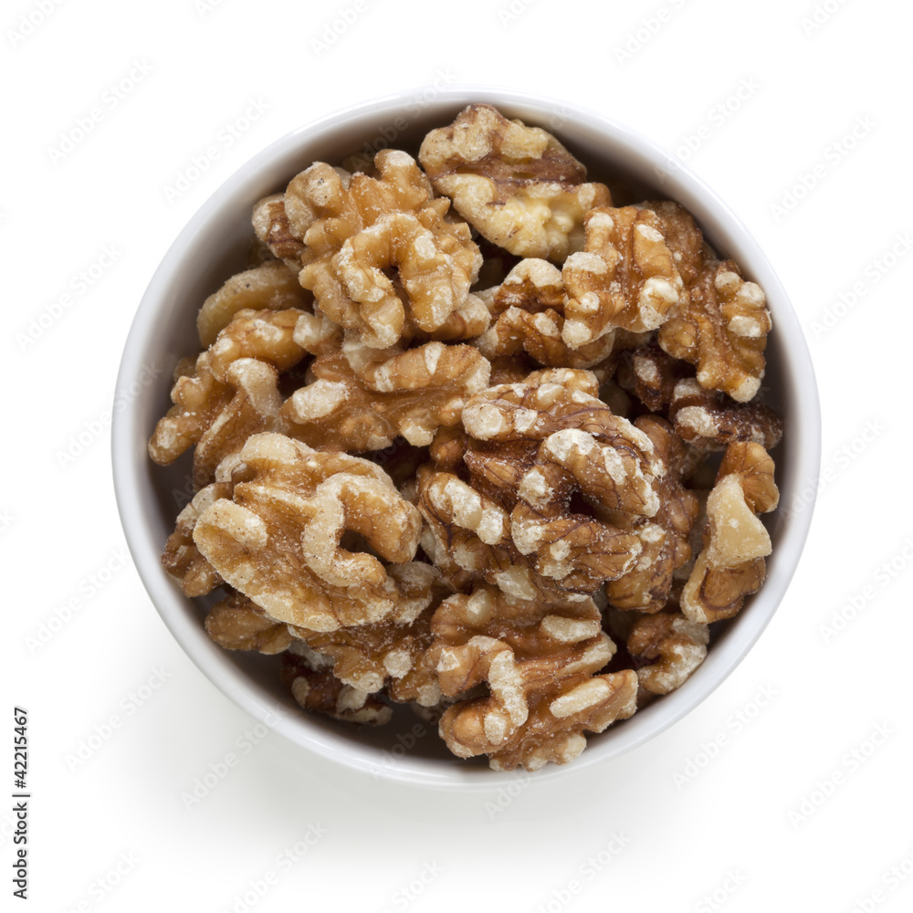 Walnuts in White Bowl over White Overhead View Walnuts in White Bowl over White Overhead View