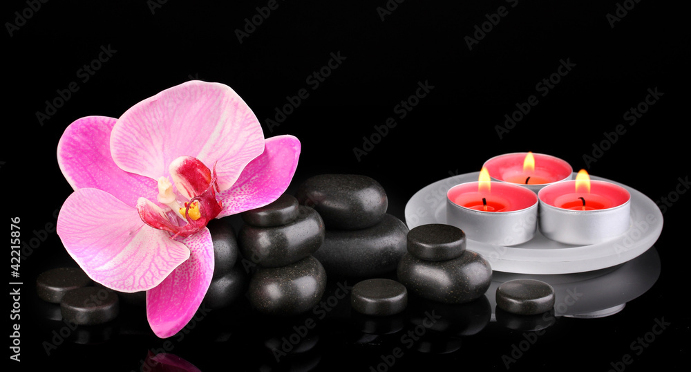 Spa stones with orchid flower and candles isolated on black Spa stones with orchid flower and candles isolated on black
