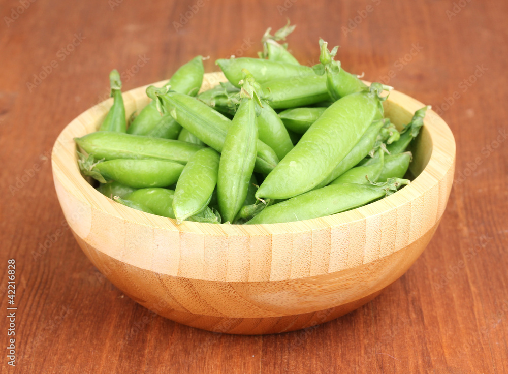 Green peas in wooden bowl on wooden background Green peas in wooden bowl on wooden background