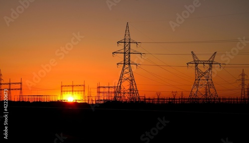 silhouette of high voltage towers in the background of sunset