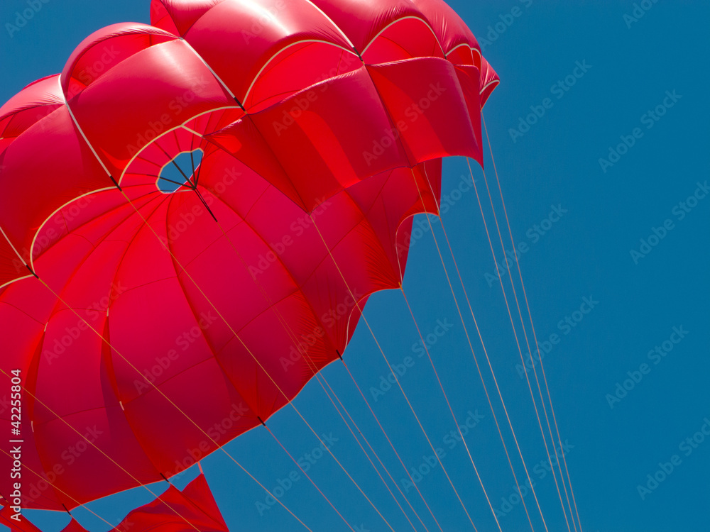 Fototapeta premium Red parachute against the blue sky