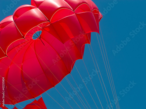 Fototapeta Naklejka Na Ścianę i Meble -  Red parachute against the blue sky