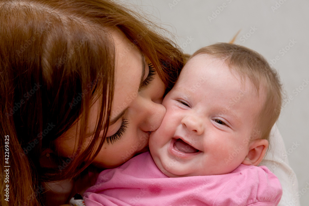 Closeup faces of young happy mother kissing newborn baby Closeup faces of young happy mother kissing newborn baby