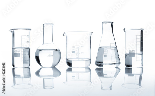 Five laboratory flasks with a clear liquid, isolated