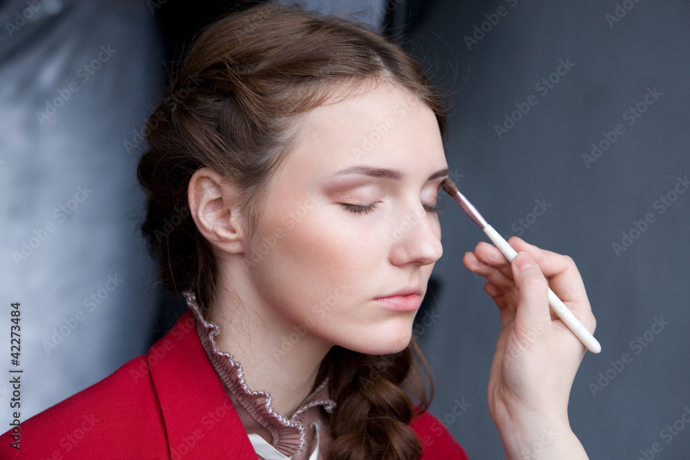 Obraz premium pretty young woman having powder applied by a make-up artist