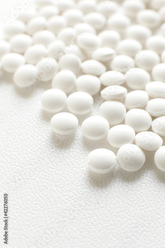 close up of white pills on white background with copy space
